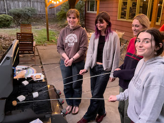 Emma, Kaia, Morgan, and Emma making s'mores at a BBQ